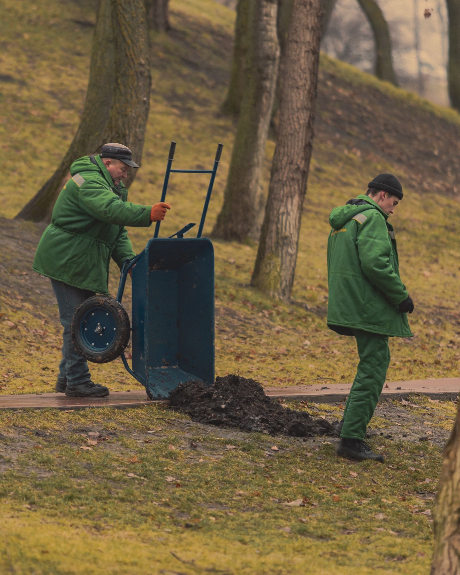 A two-person grounds crew working with a wheelbarrow